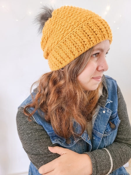 Designer wearing the Arctic Beanie in yellow, worked from the crochet winter hat pattern.