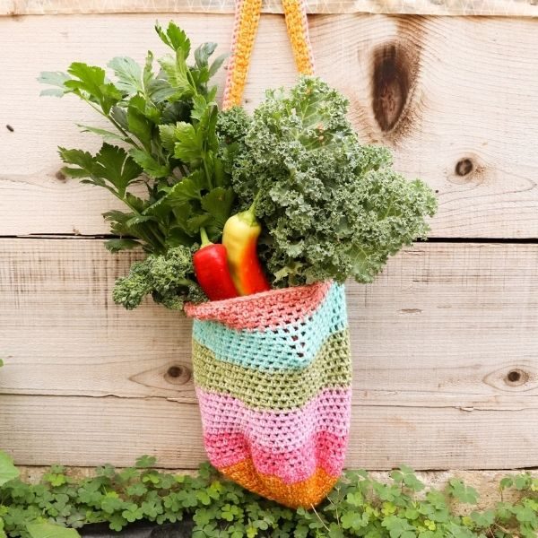 Easy crochet market bag shown hanging with vegetables to show it's ease and movement.