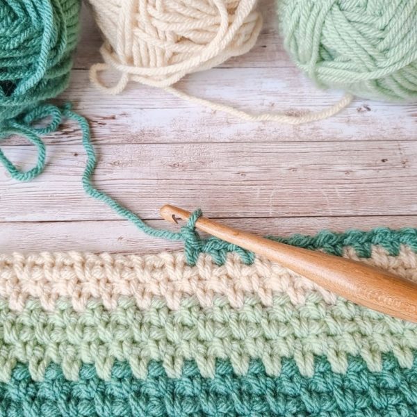 The best crochet tools for stitch definition, the Furls Streamline wood hook shown with WIP baby blanket.