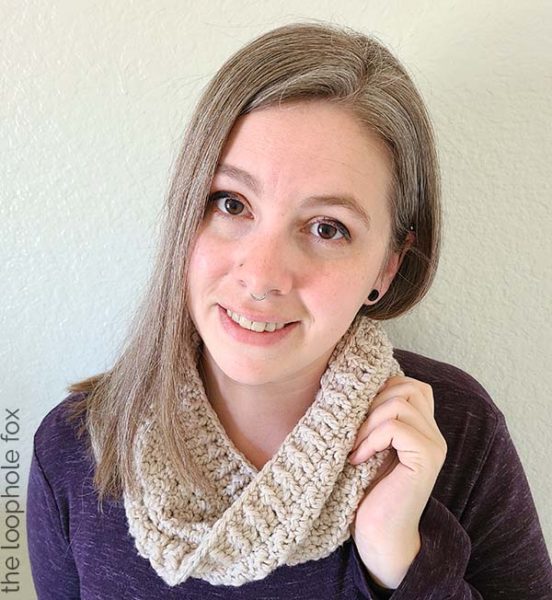 The crochet infinity cowl pattern is shown finished, worn by a woman with long hair, wearing a purple shirt.