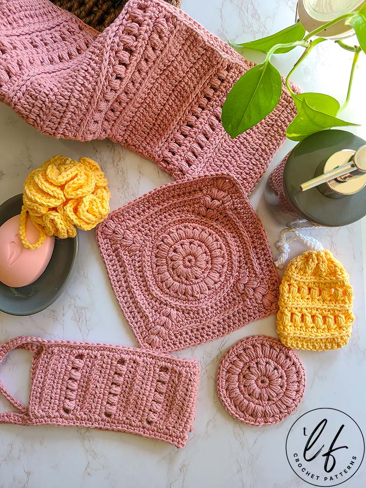 This image shows all 6 pieces of this crochet bath set laid out nicely on a marble background, with typical bathroom accessories.