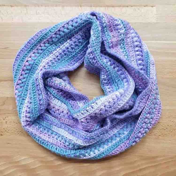 This image is of the Sea Breeze Infinity Scarf, one of the crochet projects for spring. This image shows the infinity scarf laying on a table, in it's circular form.