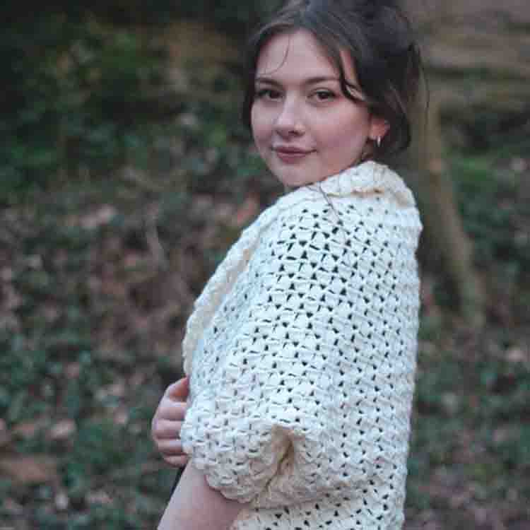This image is of the Elegant Cocoon Cardigan, one of the crochet projects for spring. This image shows a woman standing to the side and wearing the cocoon. 