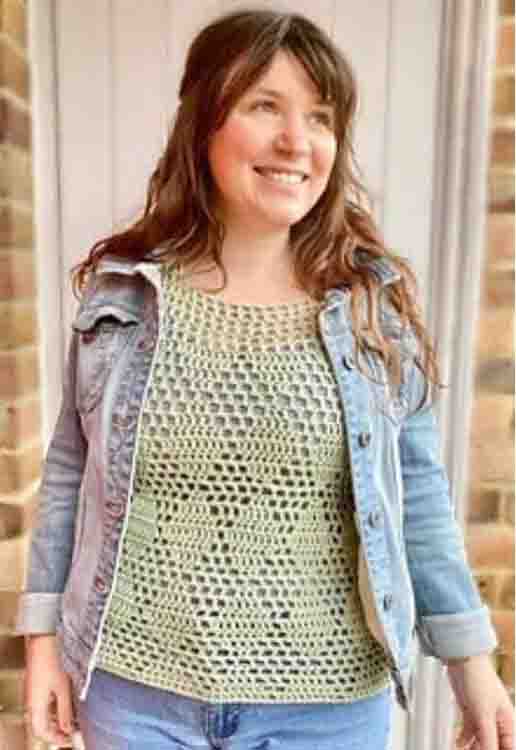 This image shows a woman wearing the Diamond Summer Top. She is standing in front of a brick wall and has paired the top with a jean jacket.