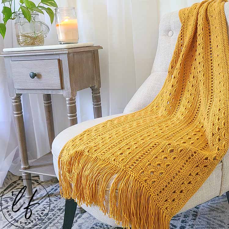 This image shows the crochet rectangle shawl in yellow, draped over a chair as if you had just set it down on your way into your home.