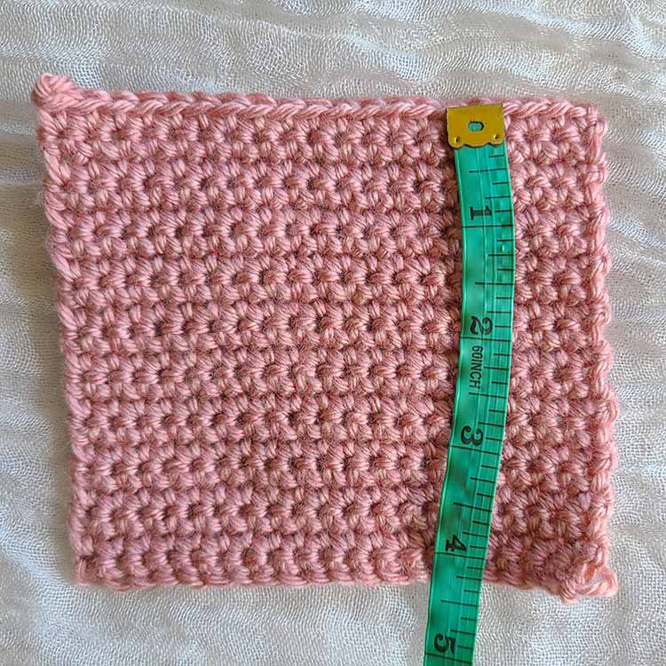 This image shows the crochet gauge swatch once more, this time with the cloth measuring tape set across it perpendicular to the stitches, or vertically to count the rows. 