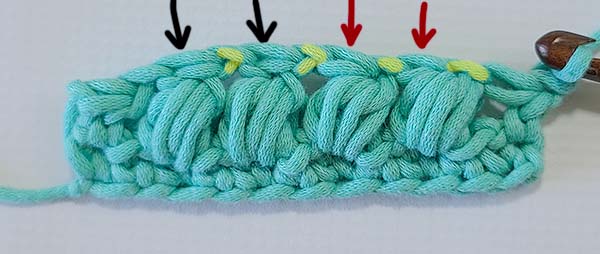 This image shows the row worked with both types of the crochet puff stitch after turning, to see the wrong side.