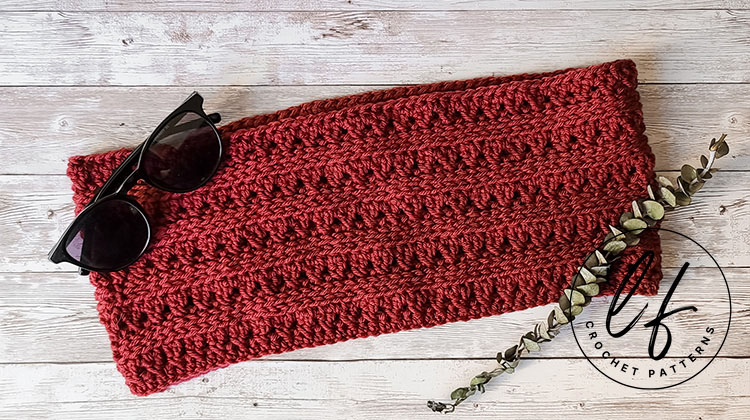 This image shows the free crochet cowl pattern sample made in red, laid flat on a wooden background.