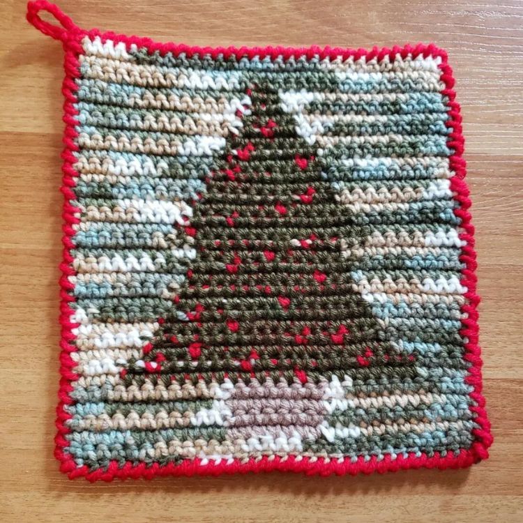 This image shows the next pattern, which is the Tapestry Crochet Christmas Tree Potholder as described above. The image shows the potholder laying flat on a wooden background.