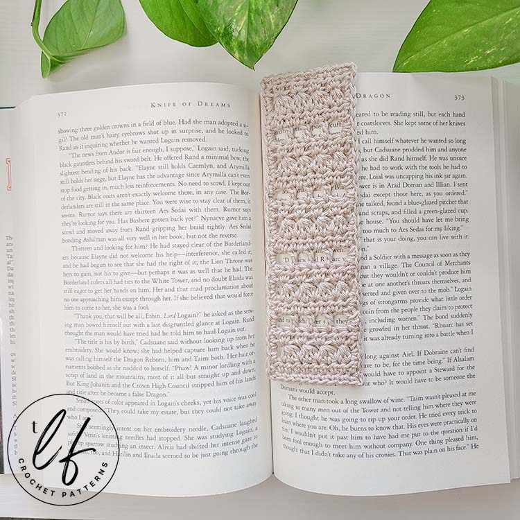 This image shows the finished project made from this Lace Crochet Bookmark Pattern in an open, hardback book that is large sized. The bookmark is made in a cream color.