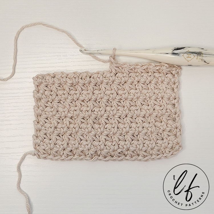 This image shows the crochet trinity stitch in a swatch. The swatch is worked in cotton yarn and several rows are created. It is on a flat white background.