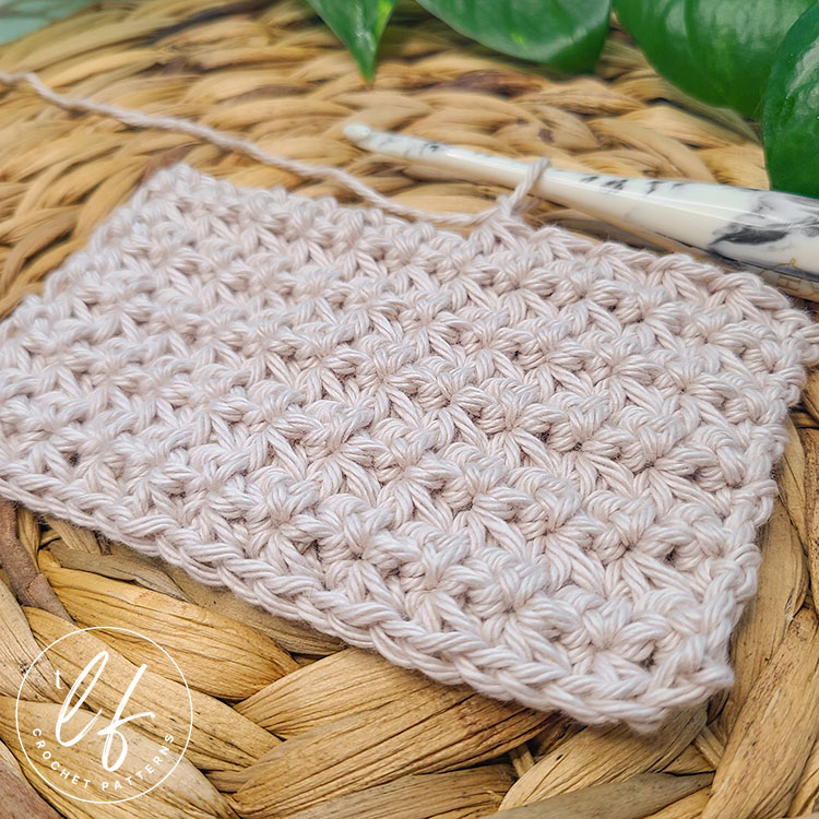 This image shows the crochet trinity stitch in a swatch. The swatch is worked in cotton yarn and several rows are created. The image is taken from an angle and close to the swatch to show the texture.